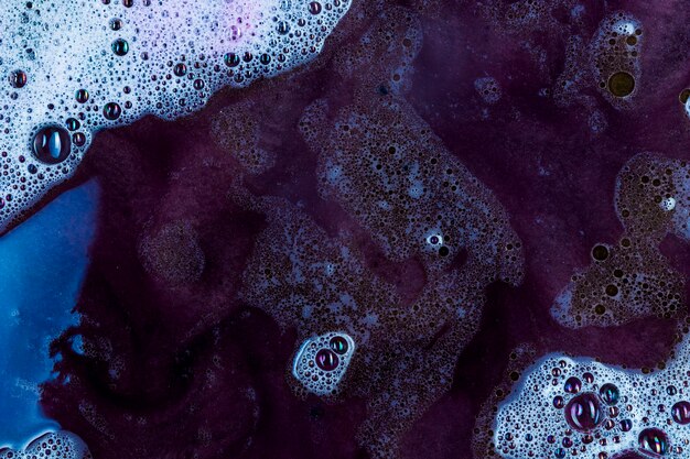Líquido escuro-violeta com espuma e gotas