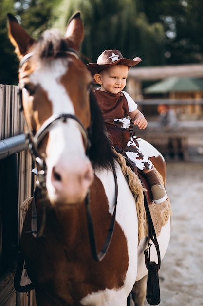 Little cowboy sentado em um cavalo