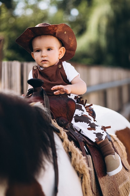 Little cowboy sentado em um cavalo