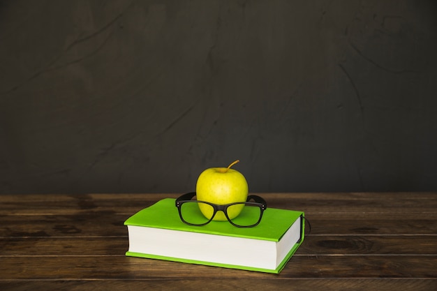 Livro colorido com óculos e maçã na mesa