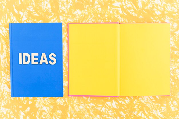 Livro de idéias perto do livro de página amarela aberta no pano de fundo amarelo
