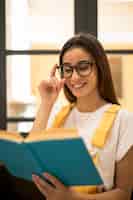 Foto grátis livro de leitura alegre estudante feminino em óculos