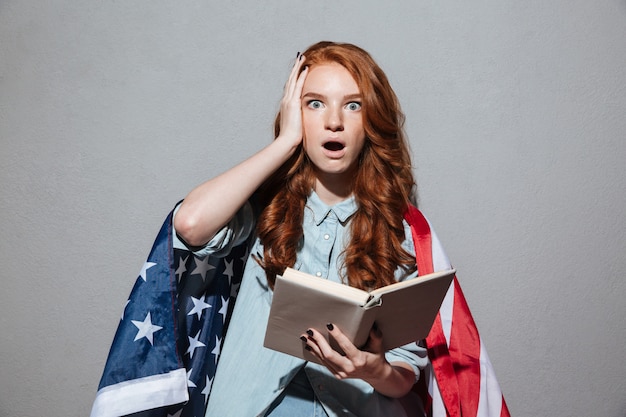 Foto grátis livro de leitura jovem ruiva chocado usando bandeira eua