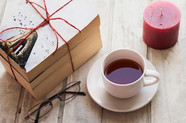 Foto grátis livros, café, vela e óculos na mesa de madeira