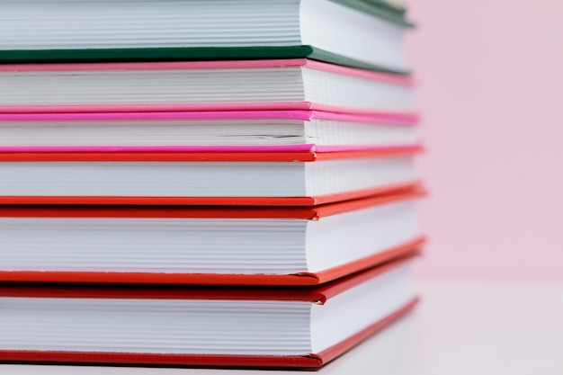 Livros coloridos com fundo rosa close-up
