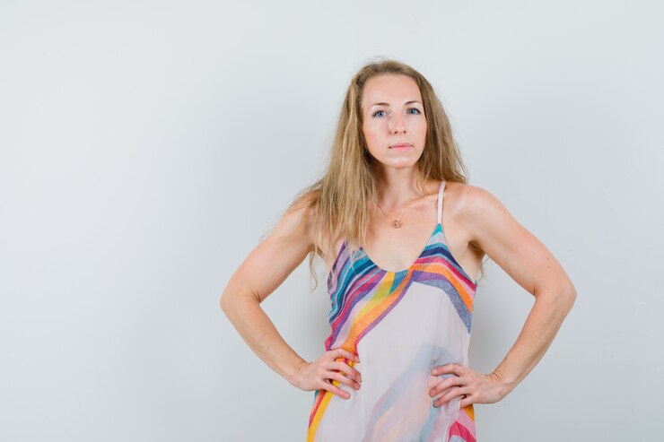 Foto grátis loira com vestido de verão de mãos dadas na cintura e parecendo confiante