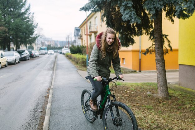 Loira jovem andando de bicicleta na estrada na cidade