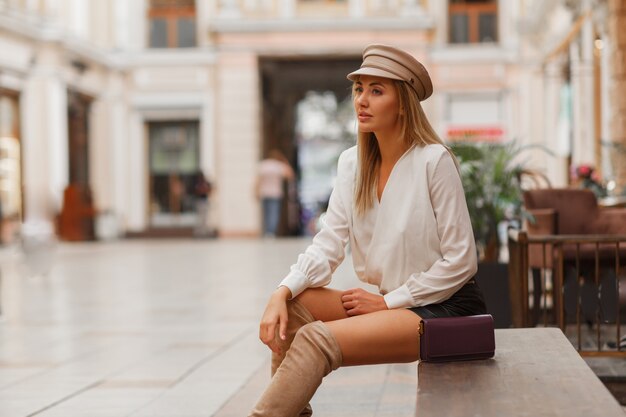 Loira sexy europeia com chapéu de chuva na moda posando ao ar livre