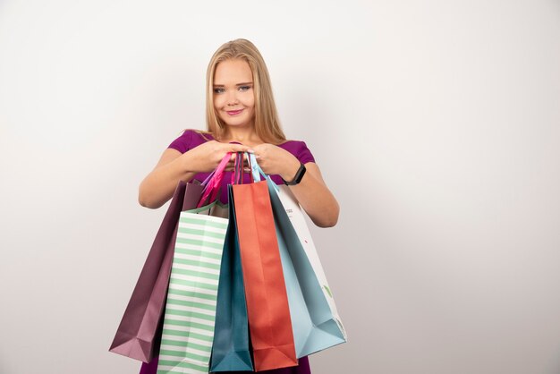 Loira viciada em compras segurando um monte de sacolas coloridas.