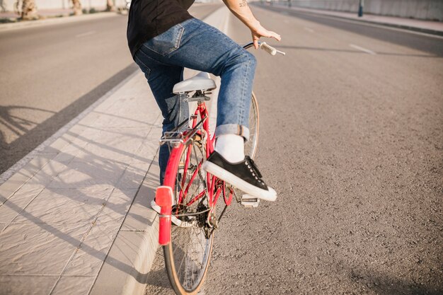 Lowsection do homem sentado na bicicleta vermelha