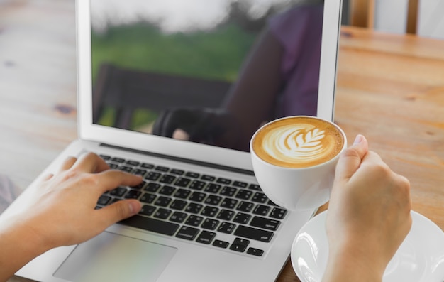 Lperson trabalhando em um laptop com uma xícara de café ao lado