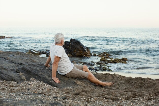 Último homem descansando na praia e admirando o oceano