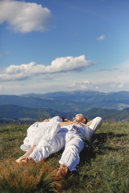 Último homem e mulher nas montanhas. Casal adulto apaixonado ao pôr do sol. Homem de camisa branca. Pessoas deitadas no fundo do céu.