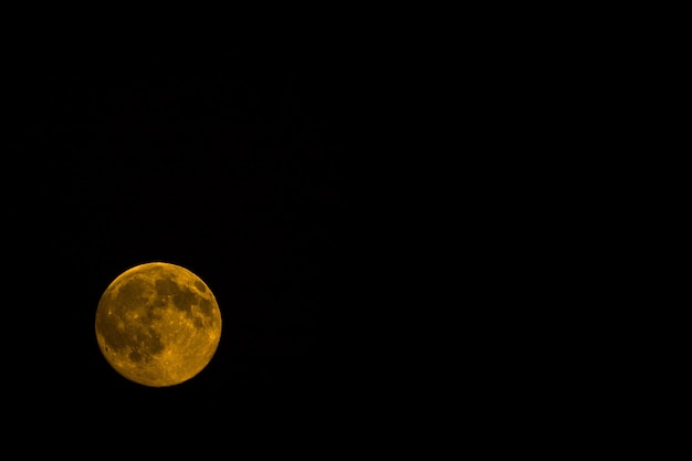 Lua laranja à noite isolada em um preto