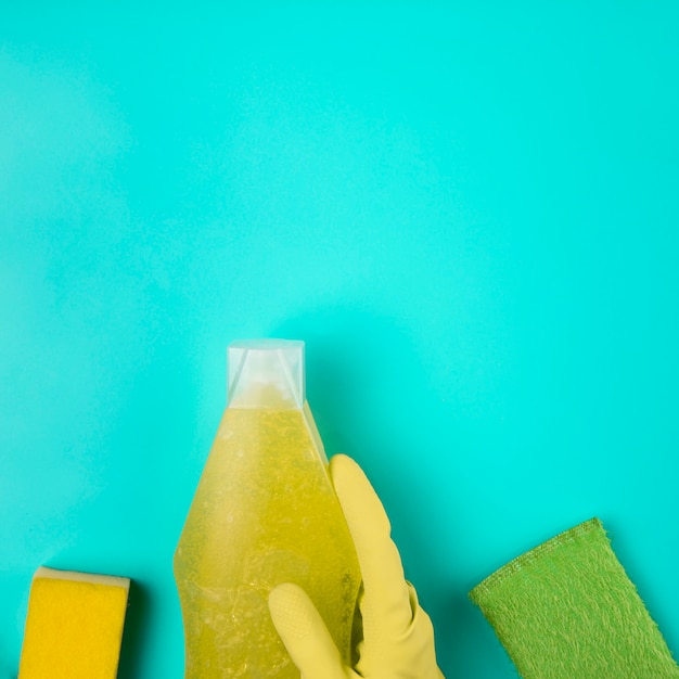 Luva amarela close-up com detergente e esponjas