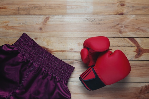 Luva de couro vermelho luva e calças de boxe na mesa de madeira