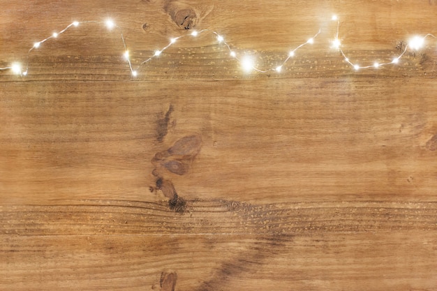 Foto grátis luzes de natal na parte superior no fundo de madeira.