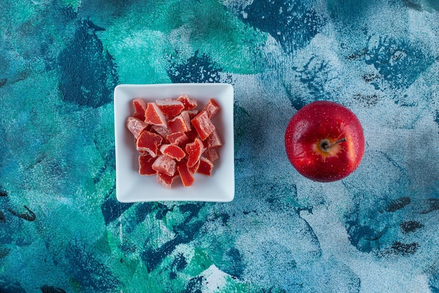 Maçã e marmelada vermelha em uma tigela, na mesa azul.
