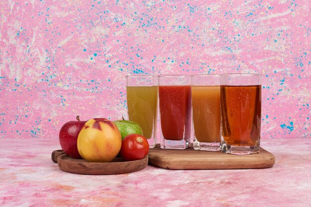 Foto grátis maçã e pêssegos com copos coloridos de suco.