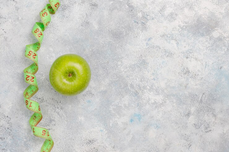 Foto grátis maçã verde fresca, fita métrica e garrafa de água fresca em concreto cinza