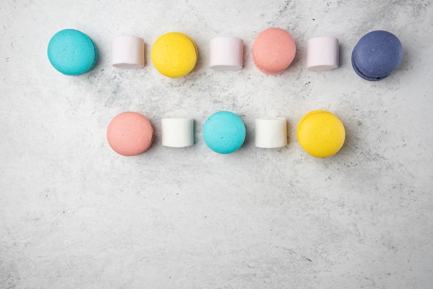 Macarons de amêndoa coloridos sobre fundo branco com marshmallows.