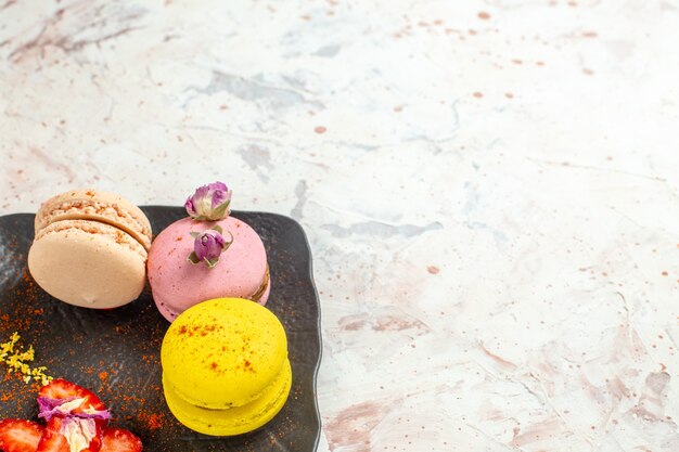 Macarons franceses de frente para dentro do prato no bolo doce de biscoito de mesa branca