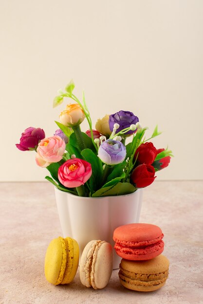 Macarons franceses deliciosos com flores na mesa rosa