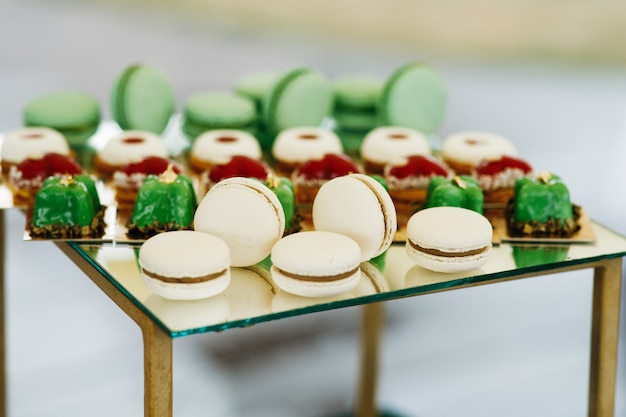 Macaroons brancos servidos com doces verdes em uma barra de chocolate