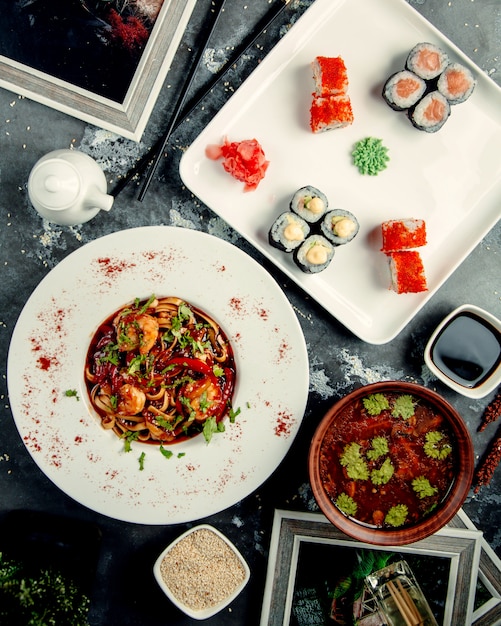 Macarrão de frango em cima da mesa com rolos de sushi