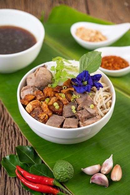 Macarrão de frango em uma tigela com acompanhamentos, comida tailandesa