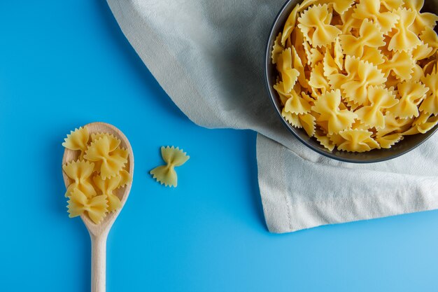 Foto grátis macarrão de macarrão liso leigos na tigela preta e colher em pano