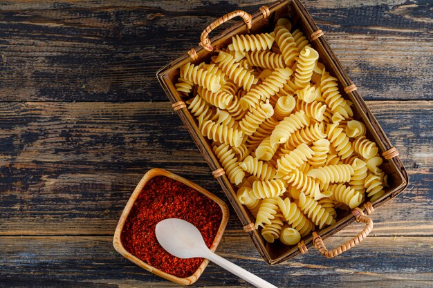 Macarrão de macarrão vista superior na bandeja com pimenta vermelha, colher em fundo de madeira. espaço horizontal para texto