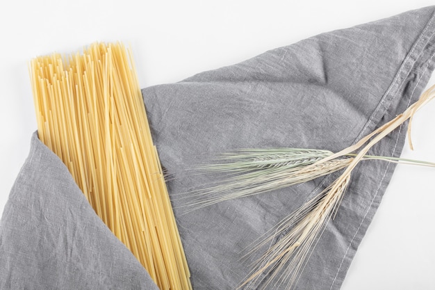 Foto grátis macarrão espaguete cru na toalha de mesa cinza com trigo.