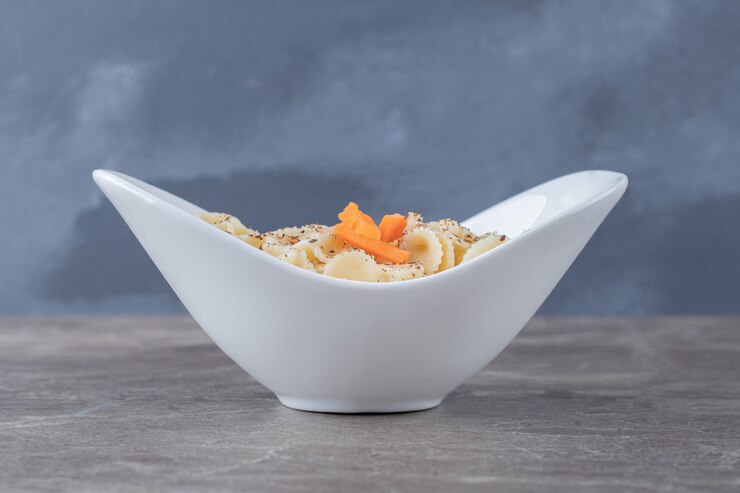 Foto grátis macarrão farfalle saboroso com molho de tomate picante em uma tigela, no mármore.