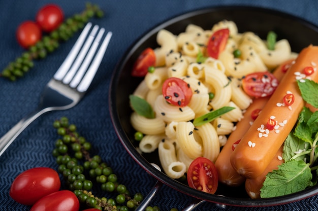 Macarrão frito e salsicha em uma frigideira.