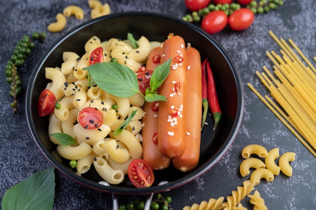 Macarrão frito e salsicha em uma frigideira.