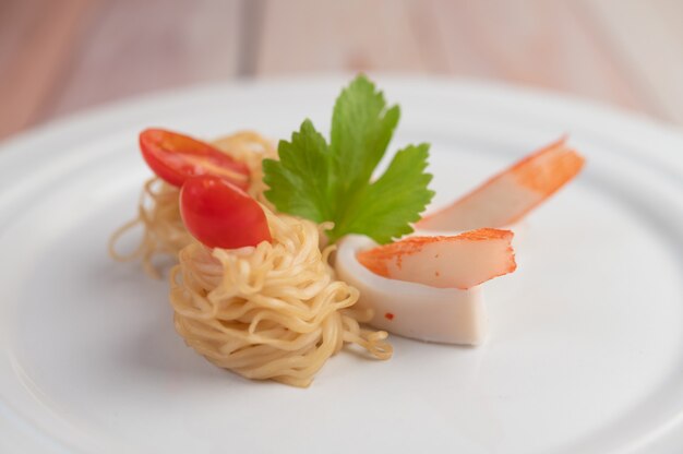 Macarrão instantâneo salteado com camarão e caranguejo em um prato branco.