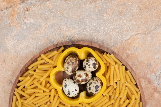 Macarrão não preparado com fatia de pimenta e ovos de codorna na placa de madeira. Foto de alta qualidade