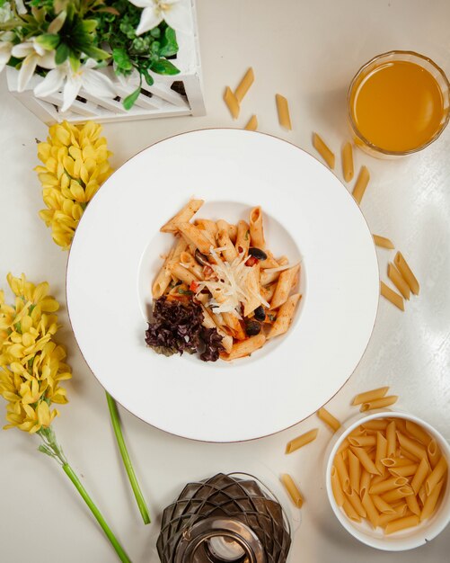 Macarrão penne com ingredientes misturados e suco de laranja.