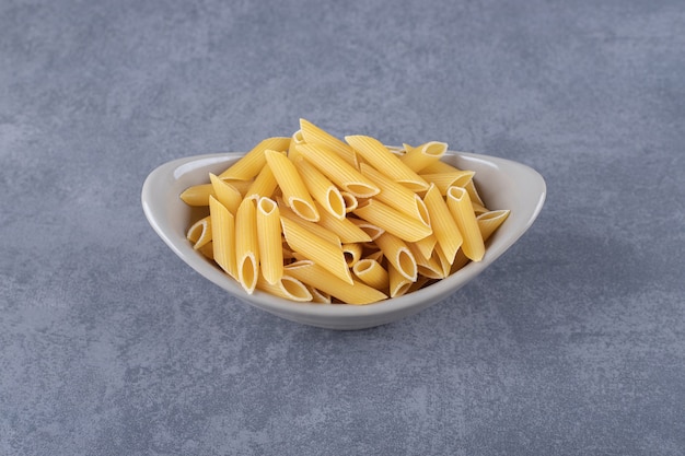 Macarrão penne cru em uma tigela de cerâmica.