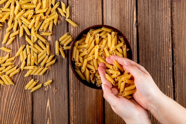 Macarrão penne de vista superior em fundo de madeira