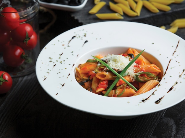 Macarrão penne em molho de tomate servido com ervas e parmesão