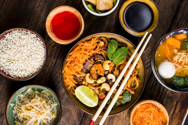 Macarrão udon de culinária tailandesa com molho de soja; arroz; brotos de feijão e sopa na mesa