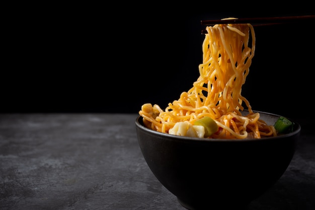 Macarronete de ovo com carne de porco e wonton roasted vermelhos na tabela.