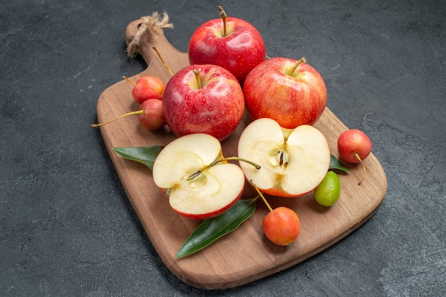 maçãs a tábua de cortar das apetitosas maçãs cítricas cerejas