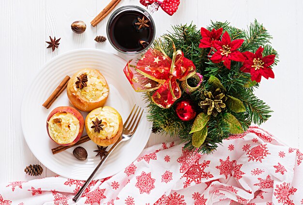 Maçãs assadas recheadas com requeijão, passas e amêndoas para o Natal em uma mesa branca. Sobremesa de comida de Natal.