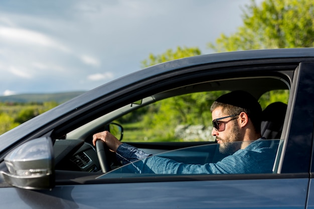 Macho brutal com óculos de sol dirigindo o carro