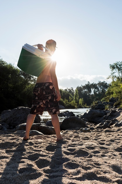 Macho com caixa legal na costa de areia perto do rio