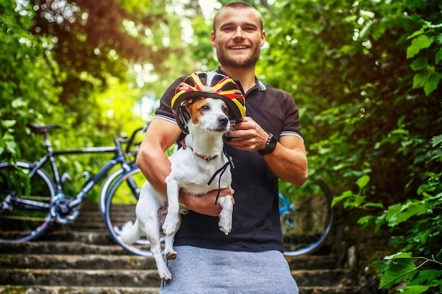 Foto grátis macho de ciclista posando com seu cachorro russel nas escadas em uma floresta.