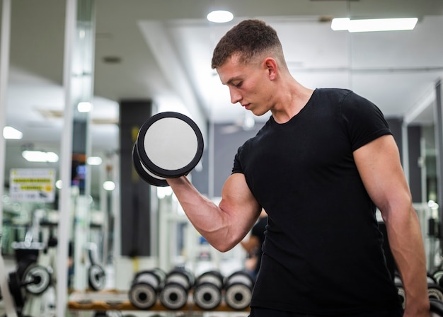 Foto grátis macho jovem de baixo ângulo, exercitando-se no ginásio